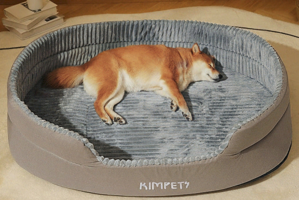 Dog lying on a gray pet bed with KIMPET branding, on a wooden floor.